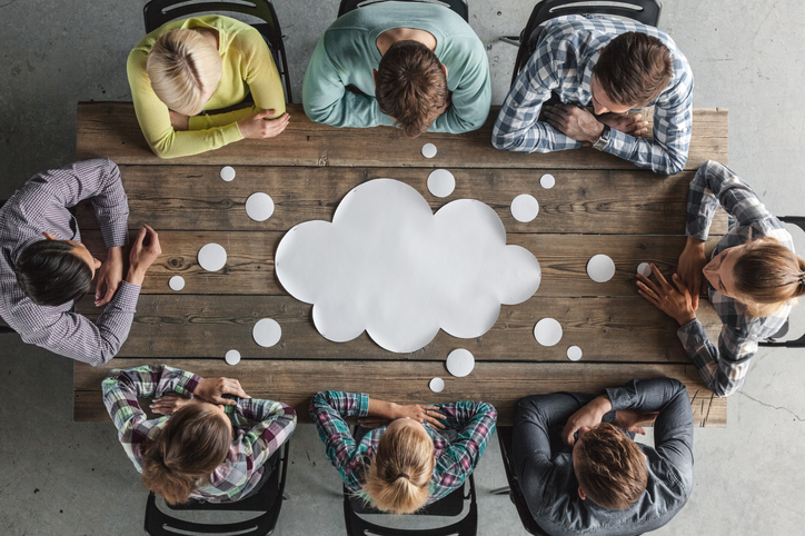 Hipster business teamwork brainstorming planning meeting concept, people sitting around the table with white paper shaped like dialog cloud