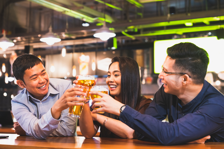 Group of happy Asian friend or office colleague coworker celebrate toast beer pint together at pub restaurant or night club. After work party, team success event or modern friendship lifestyle concept